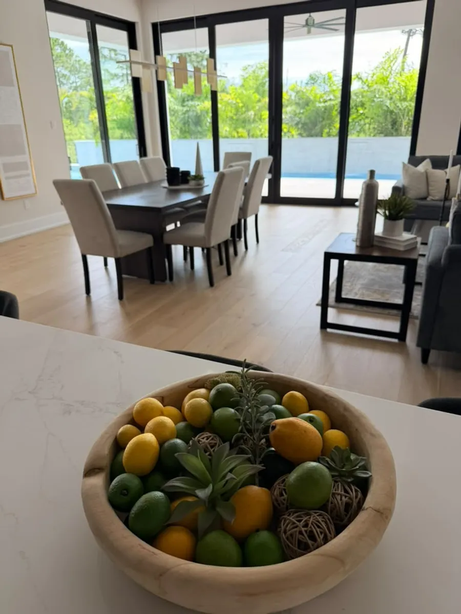 Open-concept kitchen and living area finished with engineered wood flooring, overlooking the pool
