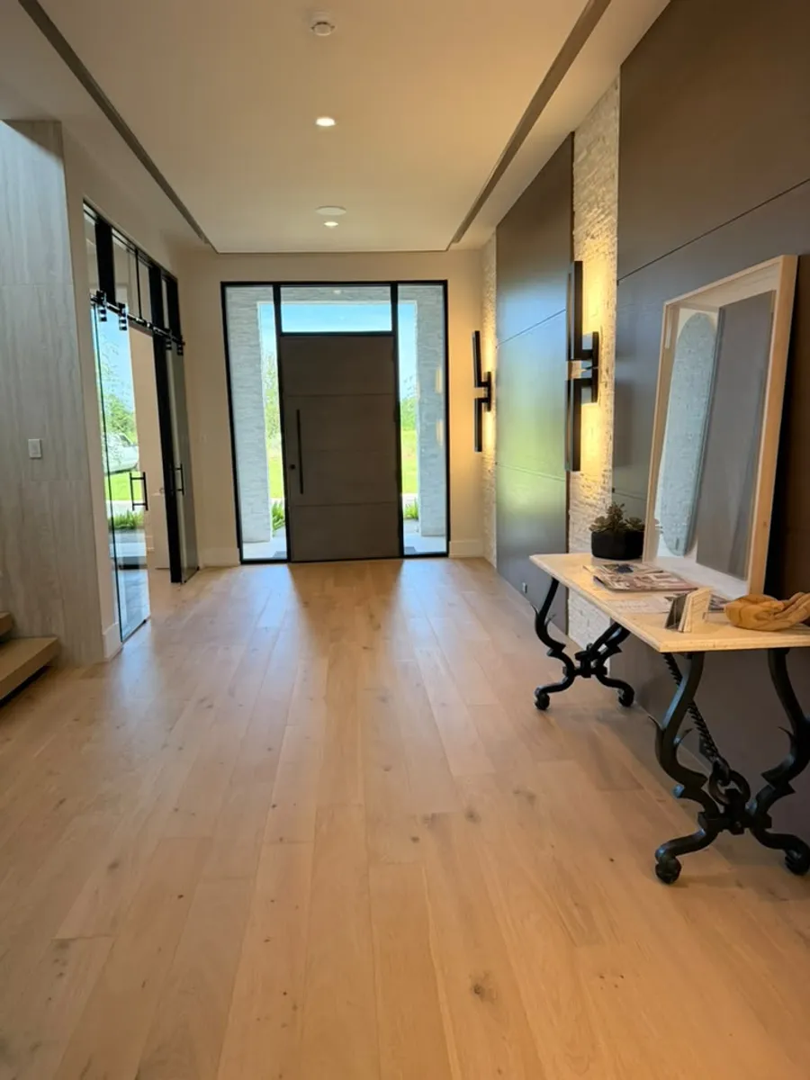 Foyer entryway finished with engineered wood flooring beside a glass front door