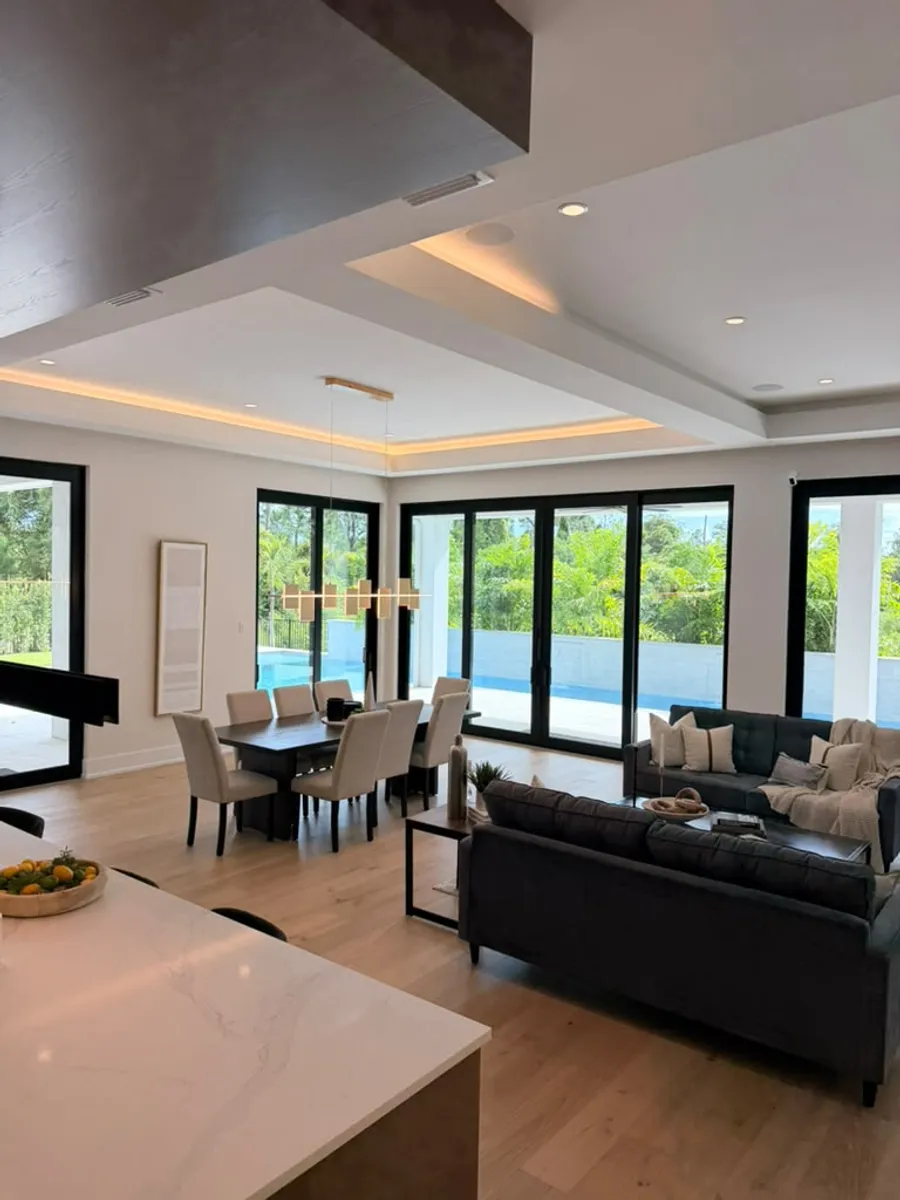Open living and dining room finished with engineered wood flooring, overlooking the pool