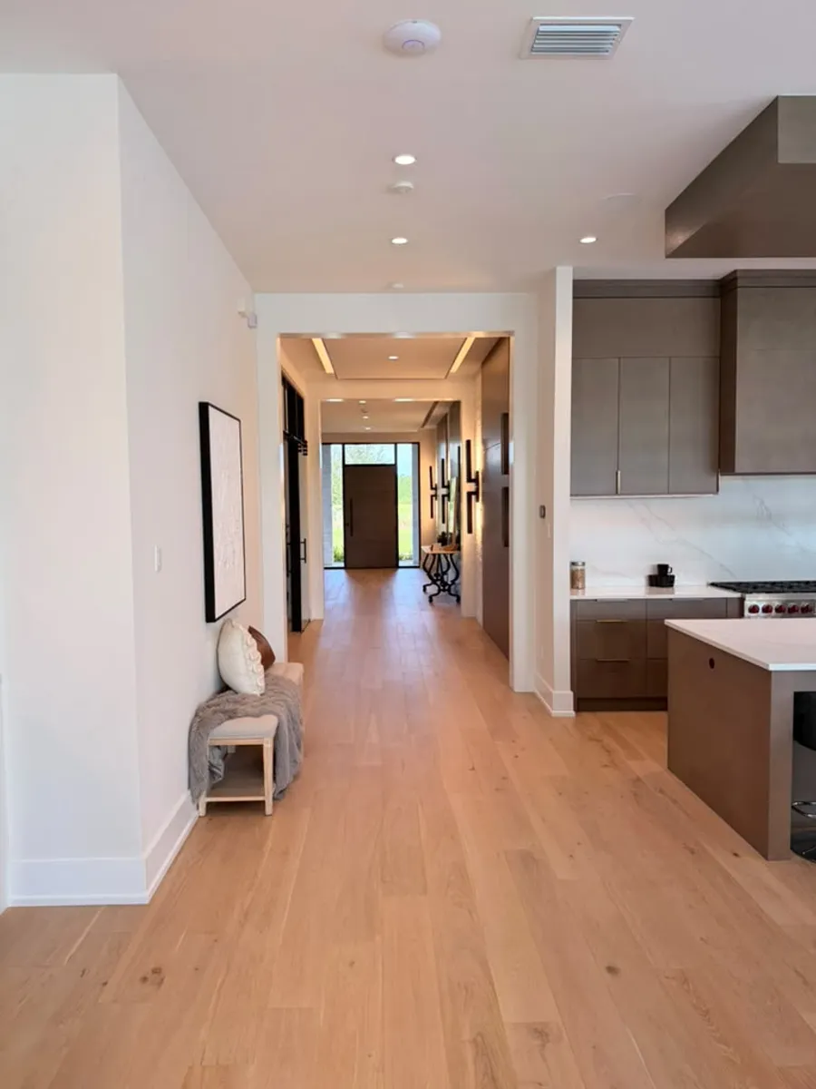 Hallway finished with engineered wood flooring connecting the kitchen and foyer