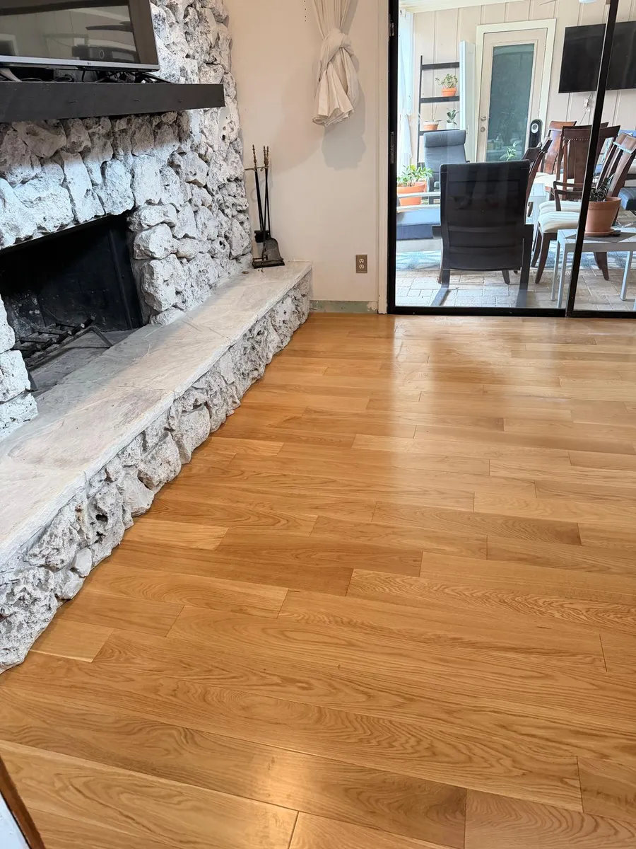 Living room finished with glossy hardwood flooring beside a stone fireplace