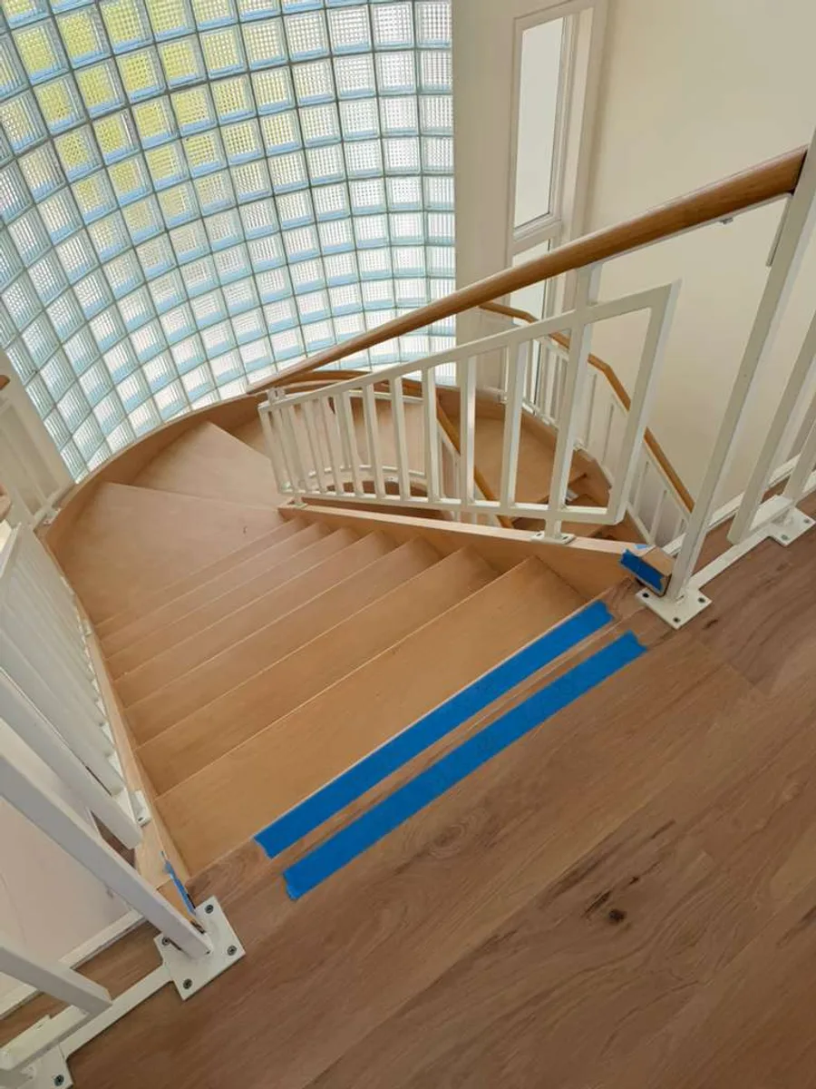 Curved staircase with light oak-tone treads and white spindles
